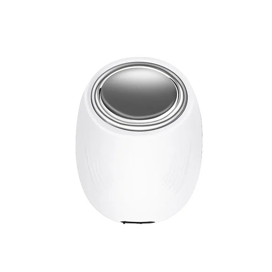 Eye Massager with Heat and Cooling White egg-shaped eye massager with a metallic circular heating and cooling surface on top.